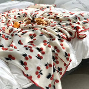 Cream-colored kids wool blanket with red and black decorbites 3d cherry appliqués and matching red pom-pom trim