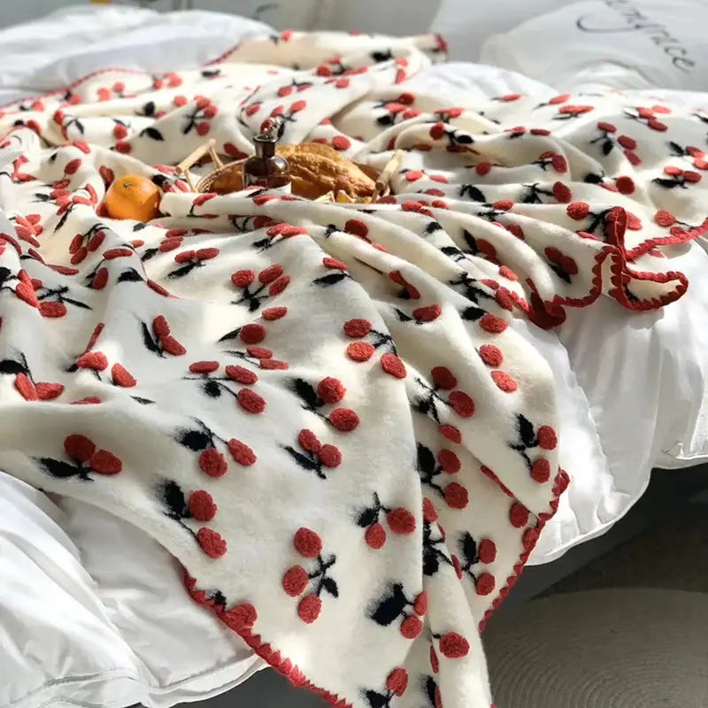 Cream-colored kids wool blanket with red and black decorbites 3d cherry appliqués and matching red pom-pom trim
