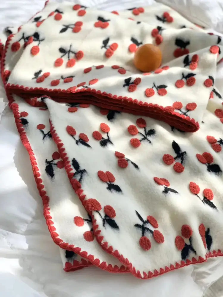 Cream-colored kids wool blanket with red and black 3d cherry embroidery and red pom-pom trim by decorbites