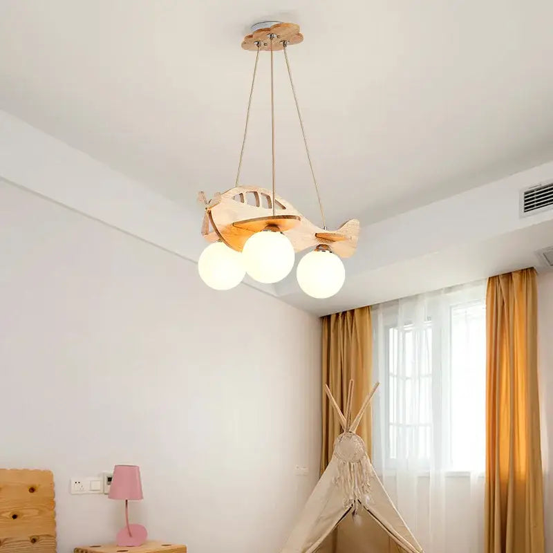 A light-colored wooden kids wood airplane pendant light with three frosted glass spherical bulbs for bedroom decorbites kids wood