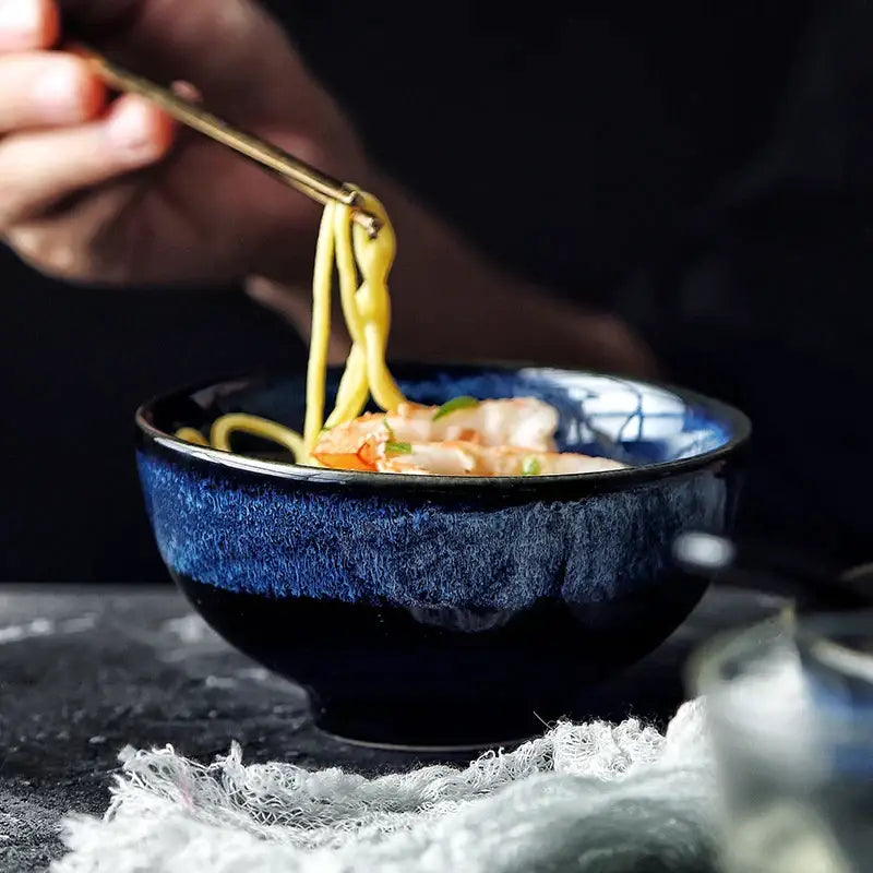 A deep blue kiln glazed ceramic bowl with speckled texture and white rim patterns for dining room ramen use