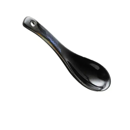 A sleek glossy black ceramic spoon with a small hole complements the kiln glazed blue speckled ramen bowl dining dish