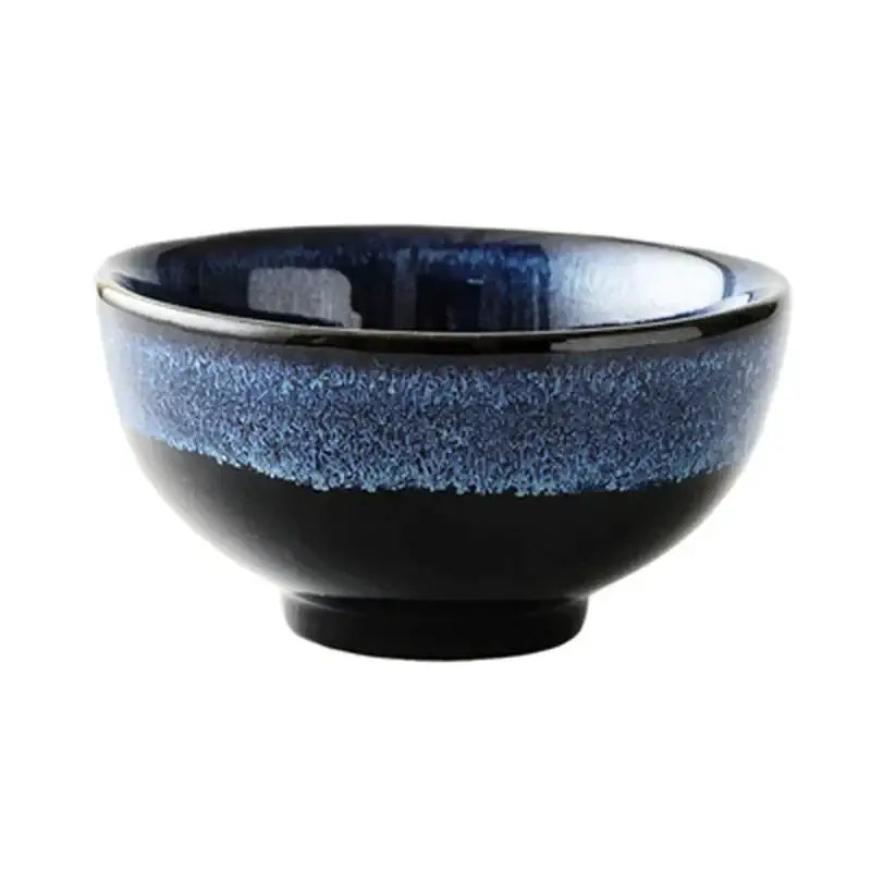 A sleek kiln glazed ceramic bowl with a glossy black base and vibrant blue speckled rim for dining room use