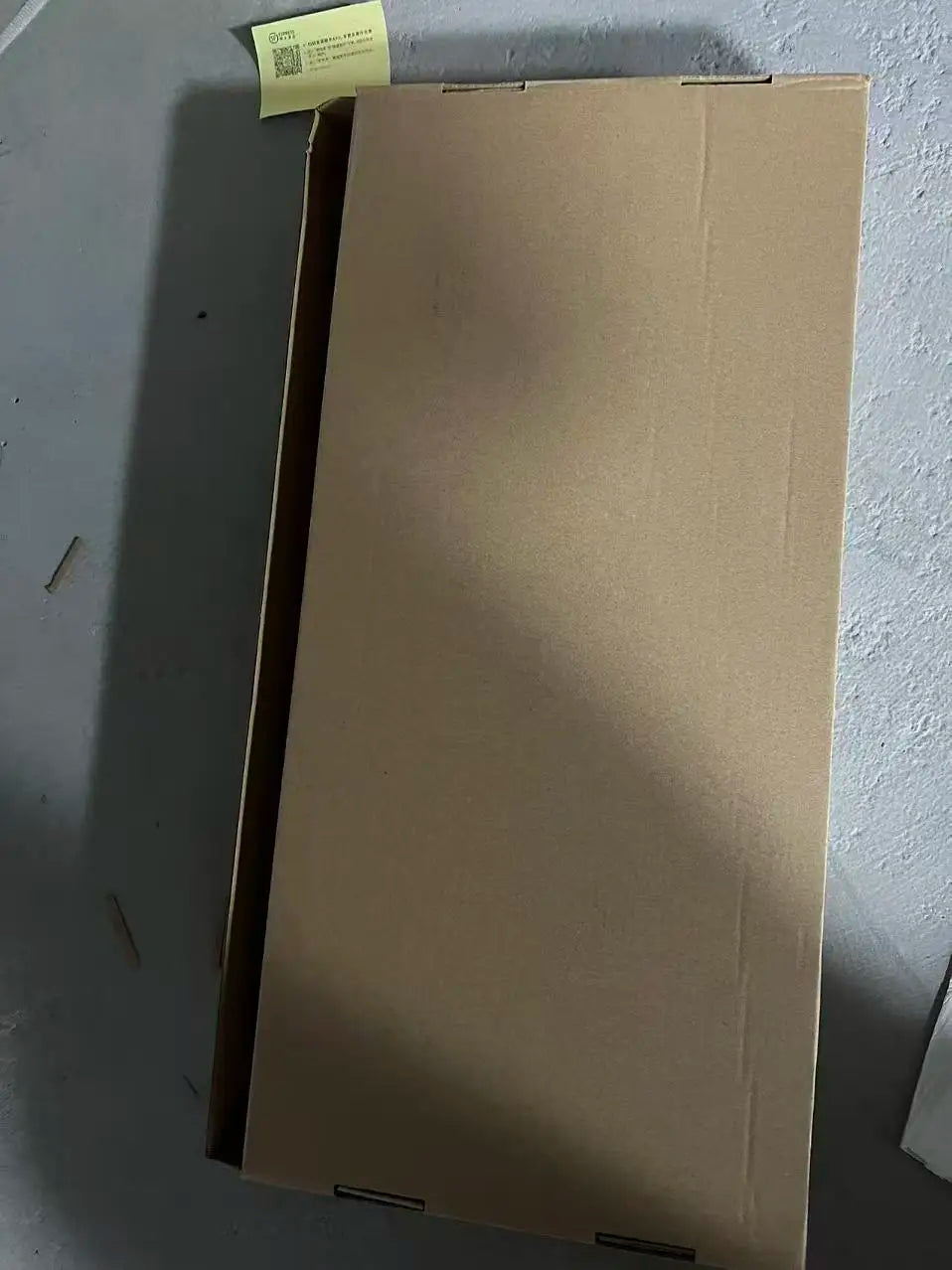 A plain brown cardboard box with a yellow shipping label containing a stainless steel brushed nickel single hole kitchen sink tap