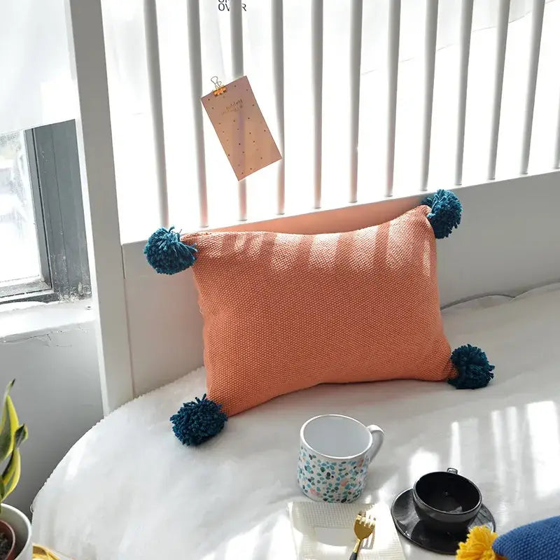 Orange textured knit cushion cover with teal pom-poms from decorbites set for blue orange and grey living room decor