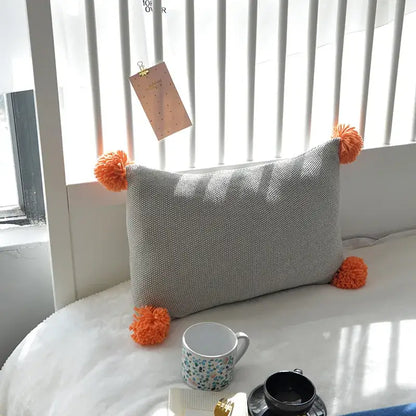 Gray textured knit cushion cover with bright orange pom-poms by decorbites for stylish living room decor