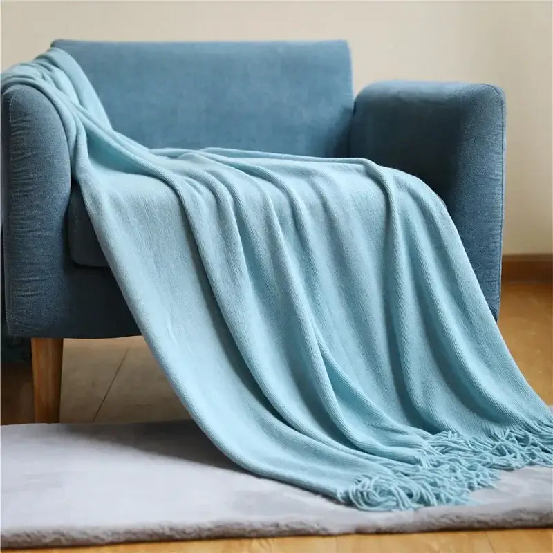 A soft light blue knitted cashmere siesta blanket with textured knit pattern and fringed edges for decorbites knitted cashmere decor