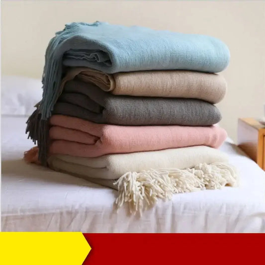 Stack of decorbites knitted cashmere siesta blankets in muted pastel tones with fringed edges for elegant bedroom decor
