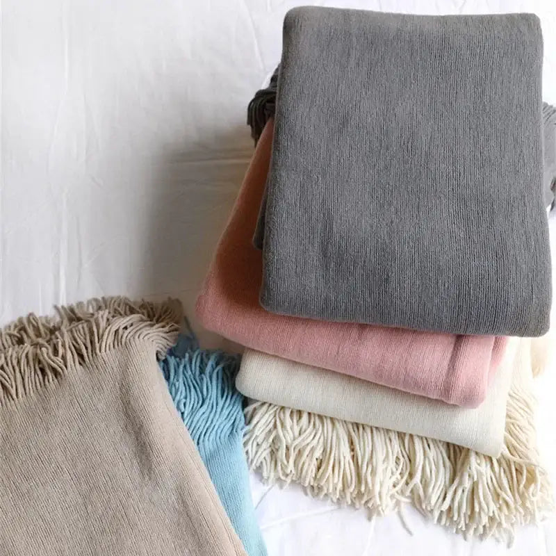 Stack of decorbites knitted cashmere siesta scarves in muted tones with fringed edges matching cashmere siesta blanket