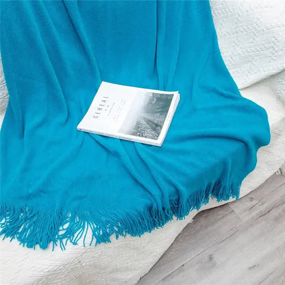 A vibrant turquoise knitted cashmere siesta blanket with soft fringed edges perfect for bedroom decorbites throw