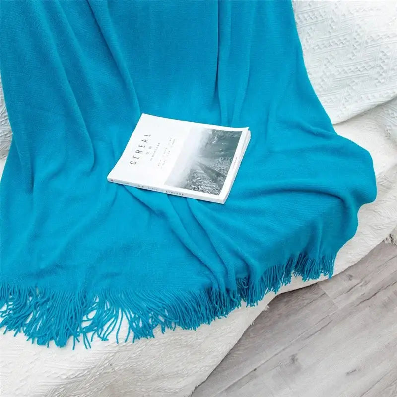A vibrant turquoise knitted cashmere siesta blanket with soft fringed edges perfect for bedroom decorbites throw