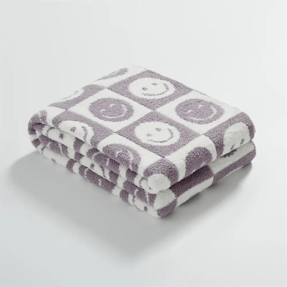 A plush knitted checkboard smile gray and white blanket with embroidered smiley faces ideal for bedroom decorbites throw
