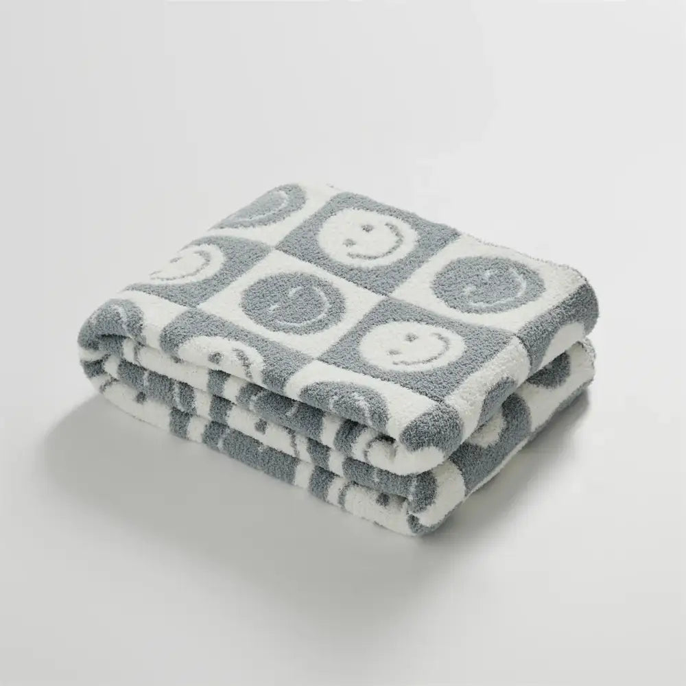 A soft knitted checkboard smile gray and white blanket with playful smiley face pattern for bedroom decorbites throw