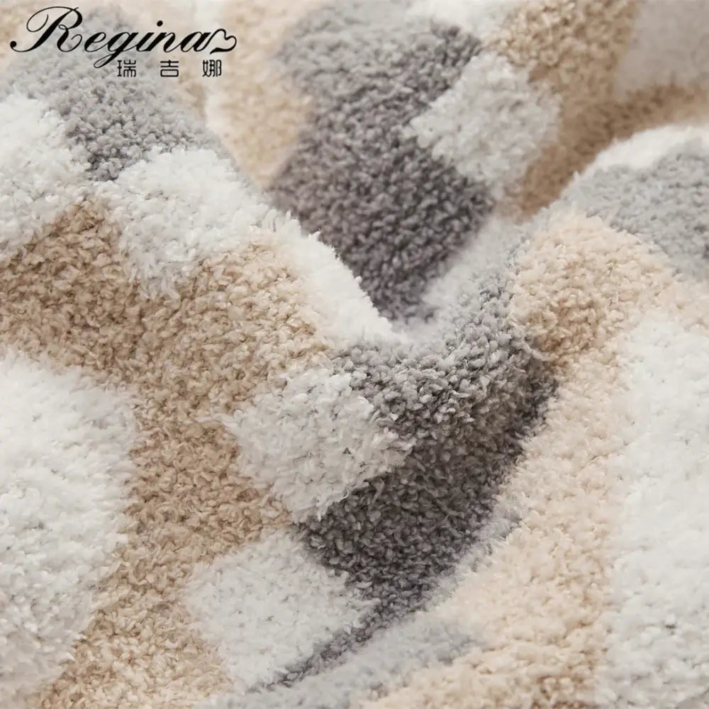 A cream and gray decorbites knitted geometric quilt blanket with a plush, textured, and fluffy surface