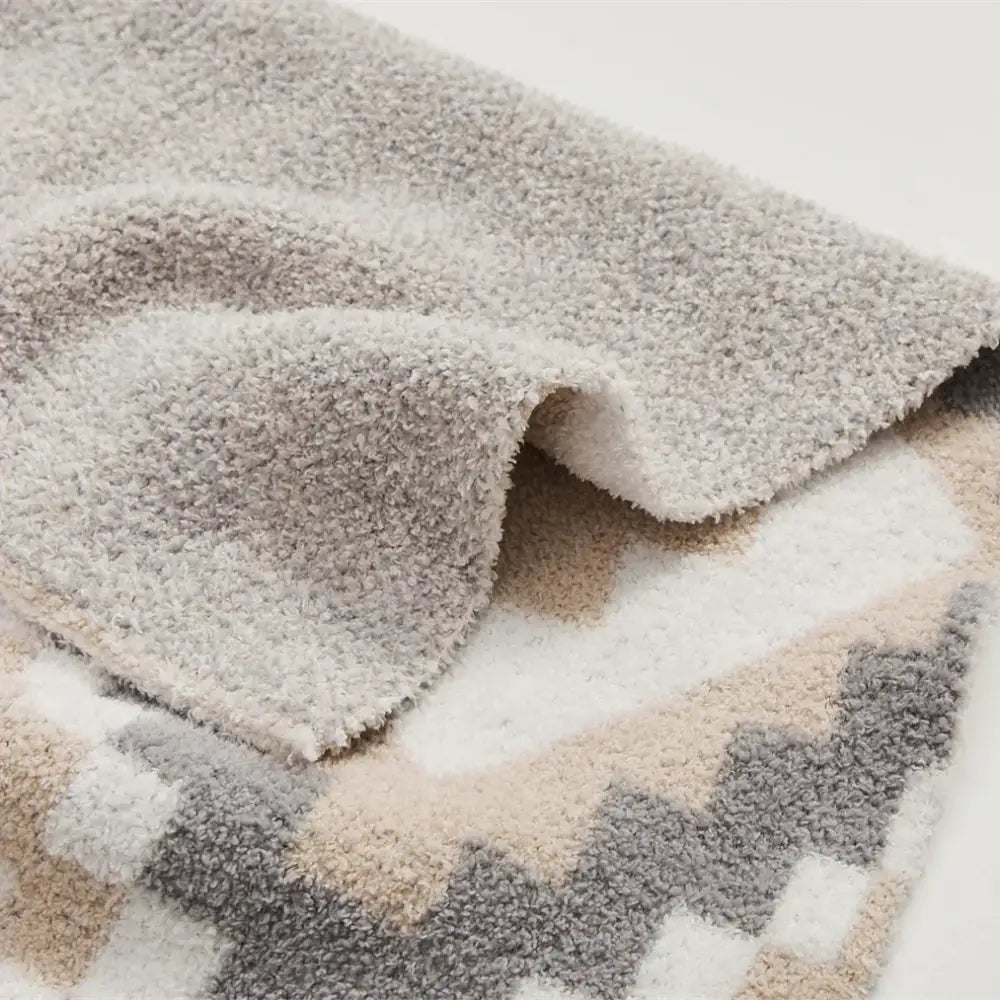 A plush decorbites knitted geometric quilt blanket in cream and gray with soft textured fabric for living room decor
