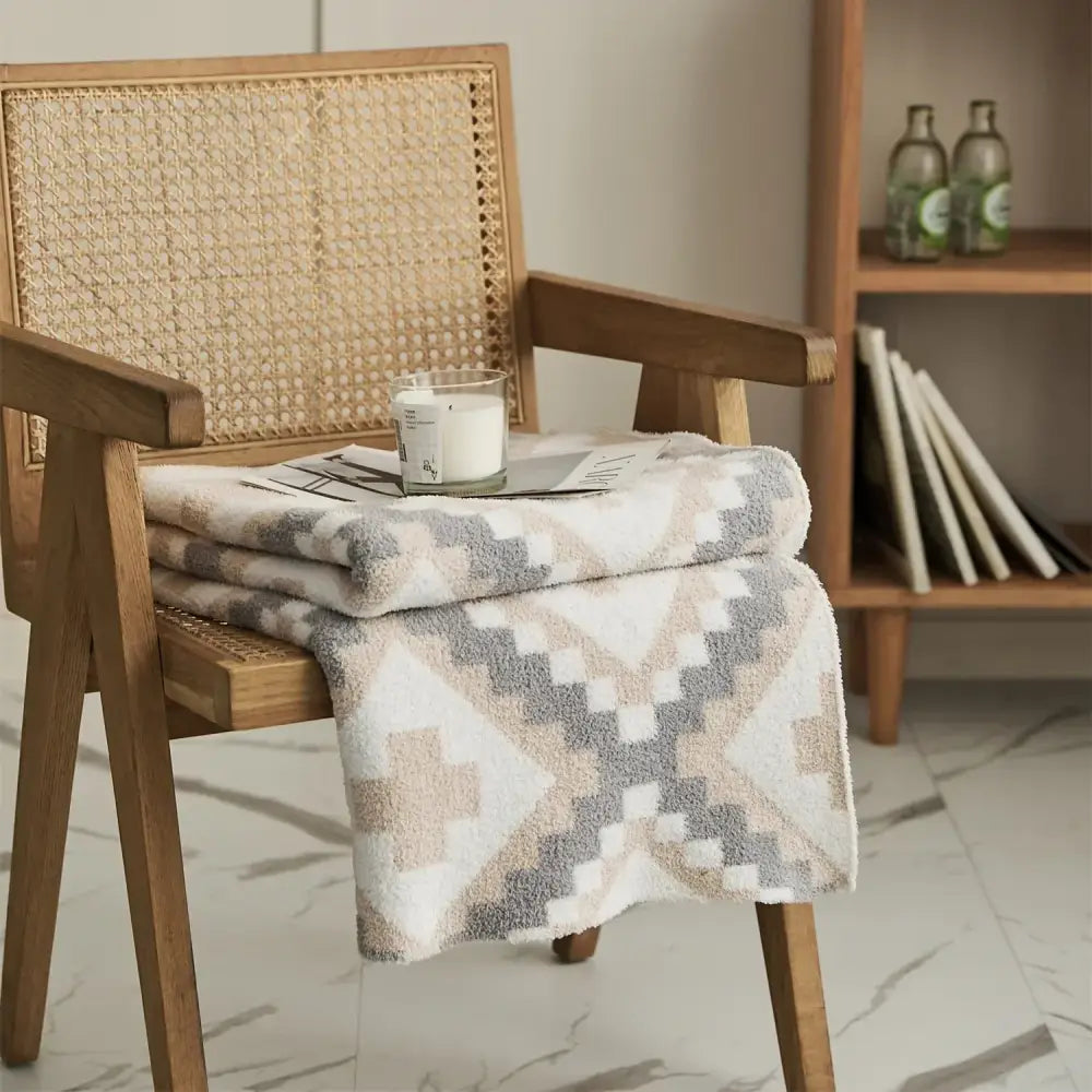 A soft plush knitted geometric quilt blanket in cream gray with a beige gray white pattern for living room decor