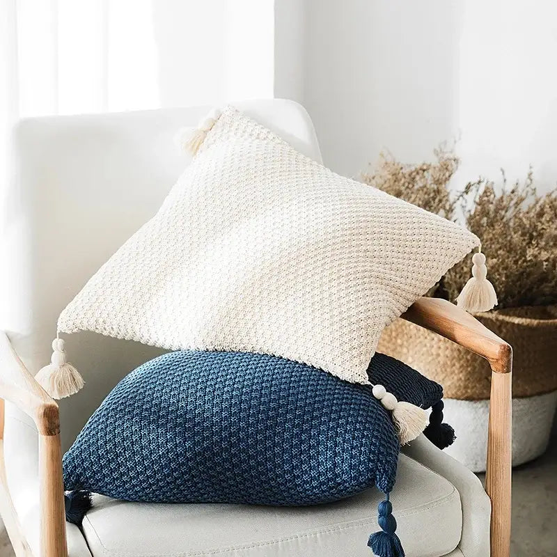 Cream-colored knitted throw pillow cover with textured weave and matching tassels for decorbites knitted grey ivory decor