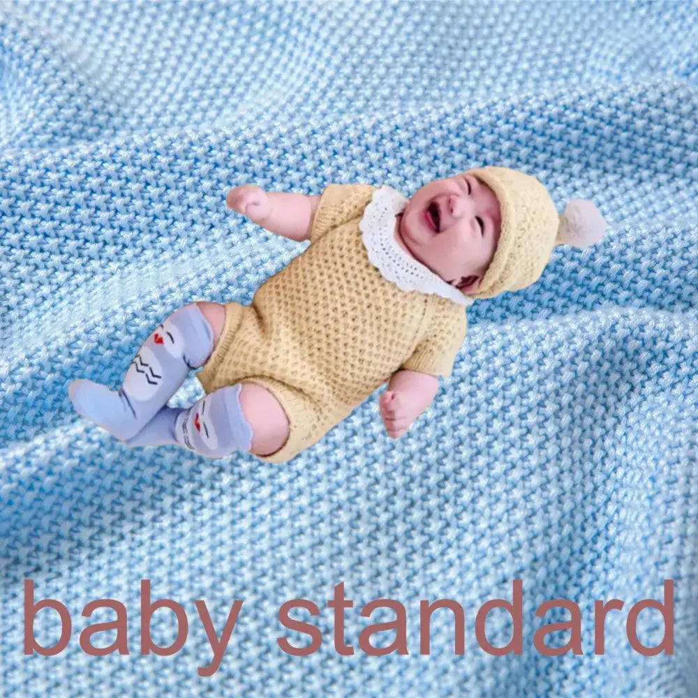 A baby dressed in a yellow knitted onesie sits on a light blue breathable bamboo baby blanket nursery quilt