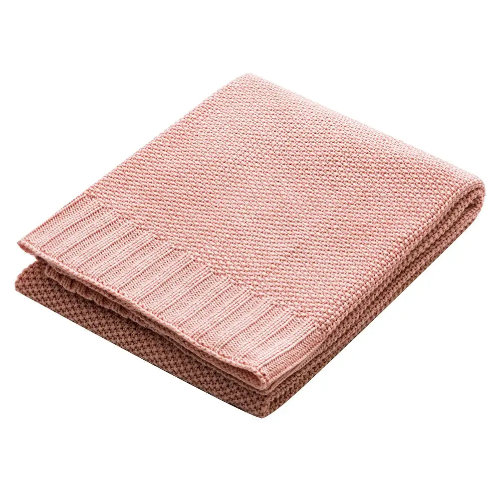 A soft pink knitted throw blanket with textured weave and ribbed edge suitable for bamboo baby blankets and nursery use