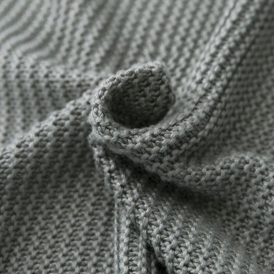 A close-up of a gray textured knitted sweater with ribbed pattern and twisted knot detail for bamboo cooling throw