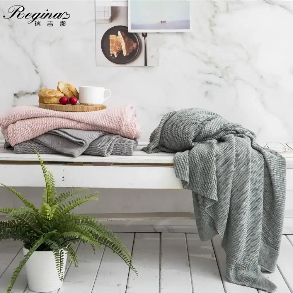 Stack of soft knitted throw blankets in muted pink and gray tones for bamboo cooling throw blanket bedding use