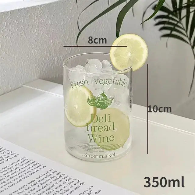 Clear glass tumbler with green lemon illustrations filled with ice and lemon slices in decorbites korean glass cups