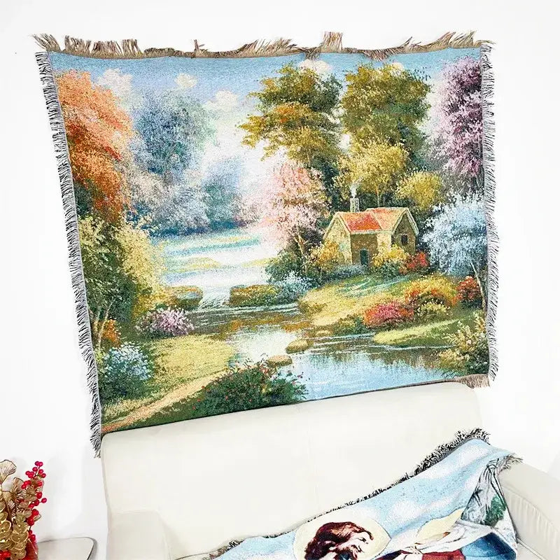 A decorbites jacquard sofa blanket featuring a woven pastoral scene with autumn trees and a cottage by a river
