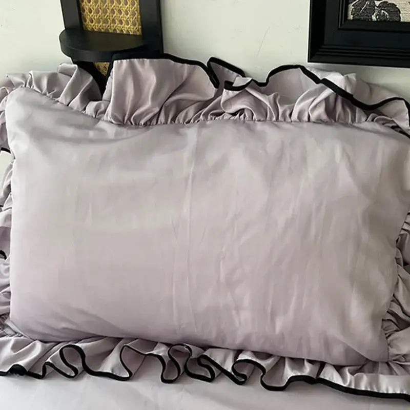 A soft lavender satin pillow sham with delicate black-trimmed ruffled edges from decorbites cooling silky bedding set