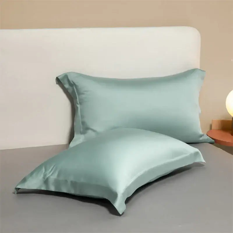 Two mint green satin egyptian cotton pillowcases with a smooth glossy finish from a cotton pillowcase set