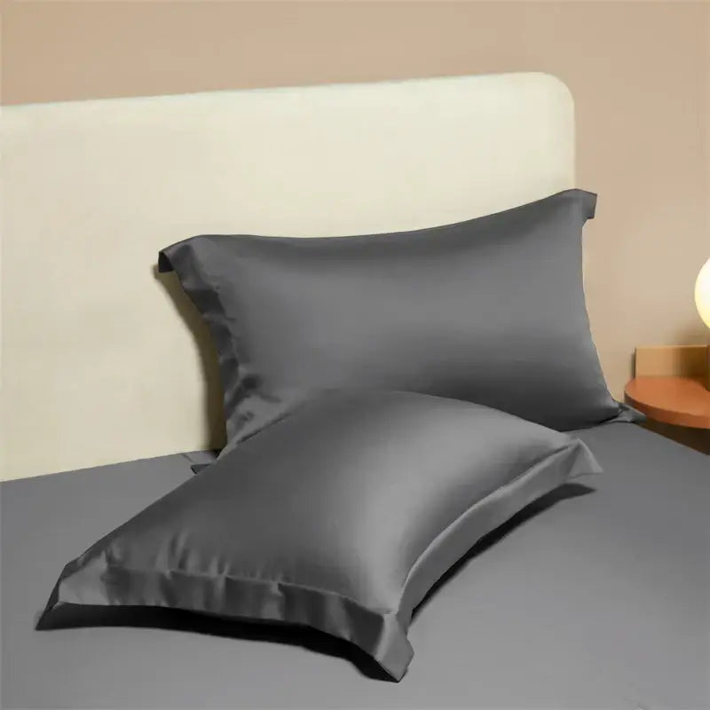 Two dark gray satin egyptian cotton pillowcases with smooth glossy finish in a cotton pillowcase set for bedroom use