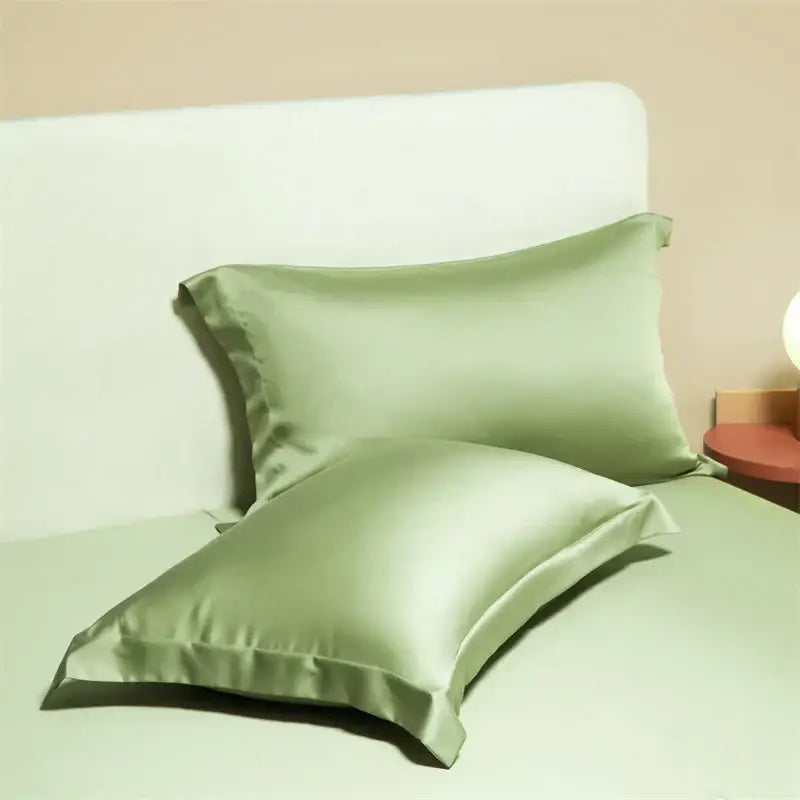 Two sage green satin egyptian cotton pillowcases with smooth glossy finish in a cotton pillowcase set for bedroom use