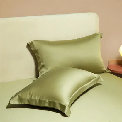 Two sage green satin egyptian cotton pillowcases with a smooth glossy finish from a cotton pillowcase set