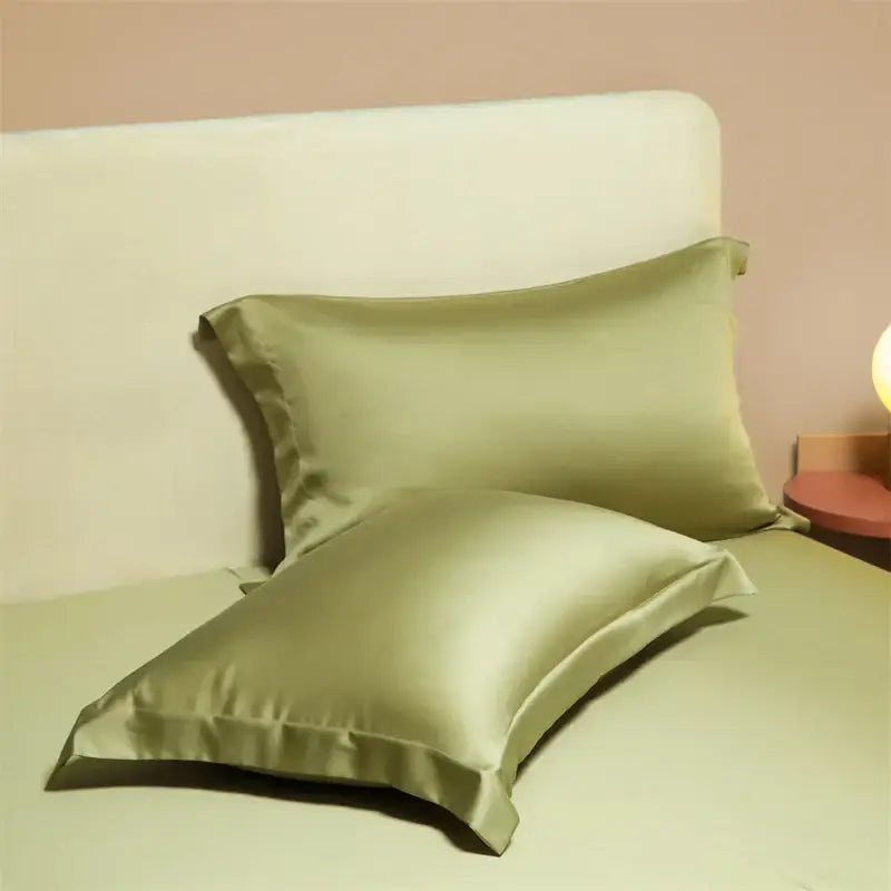 Two sage green satin egyptian cotton pillowcases with a smooth glossy finish from a cotton pillowcase set