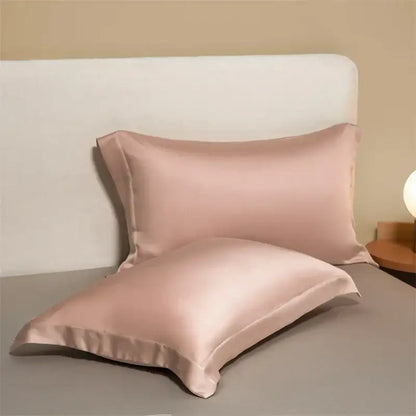 Two blush pink satin egyptian cotton pillowcases with a smooth glossy finish in a cotton pillowcase set