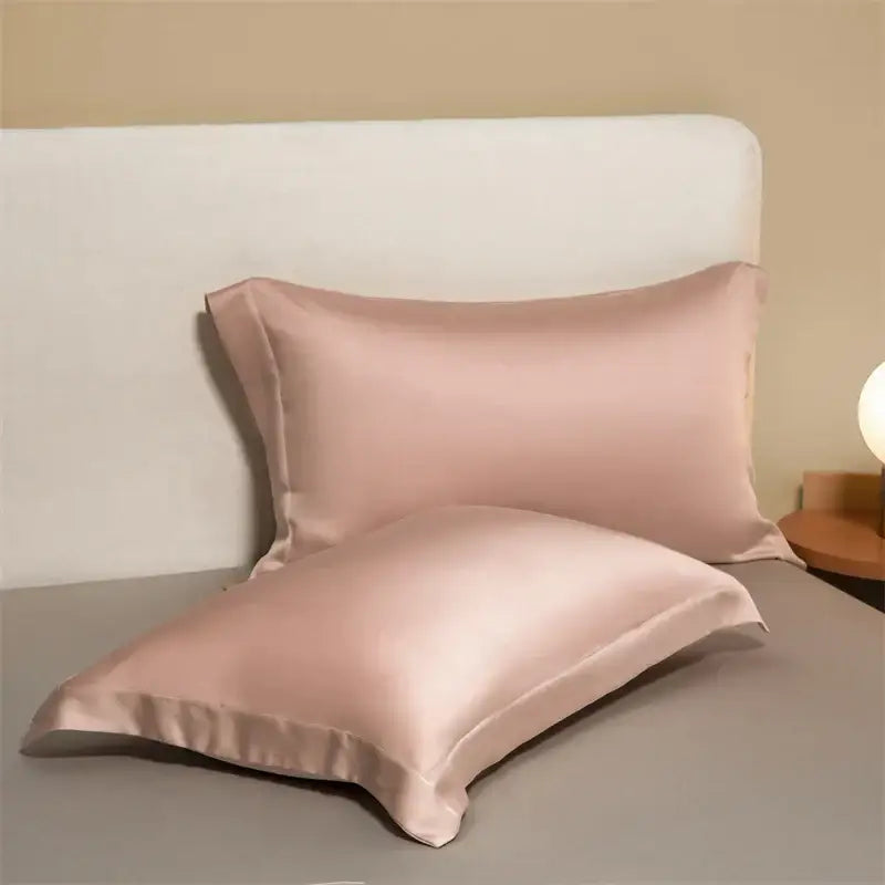 Two blush pink satin egyptian cotton pillowcases with a smooth glossy finish in a cotton pillowcase set