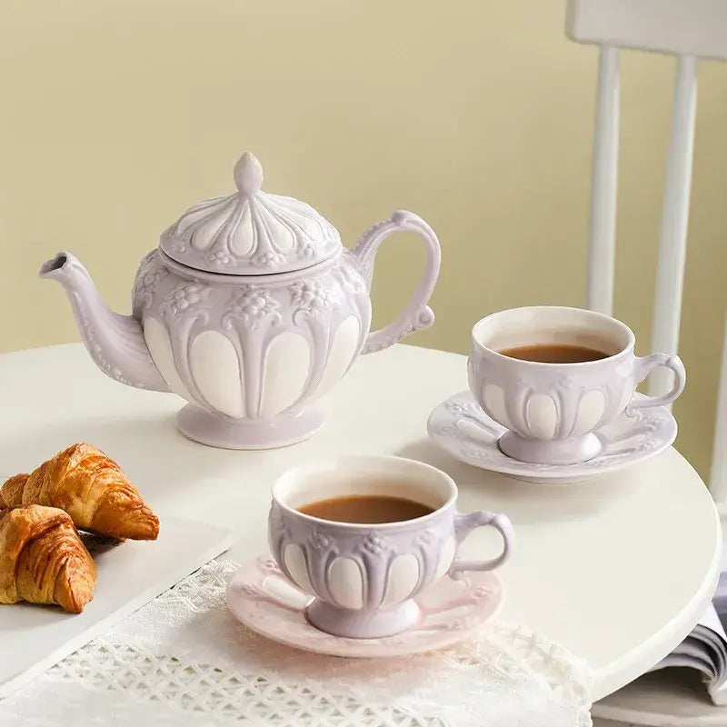A lavender floral elegant porcelain tea set with intricate embossing including a teapot and matching cups for decorbites
