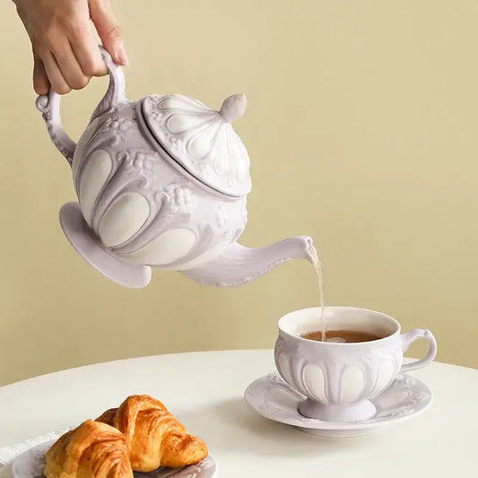 A delicate lavender elegant porcelain tea set with intricate floral embossing pouring tea into matching cup and saucer
