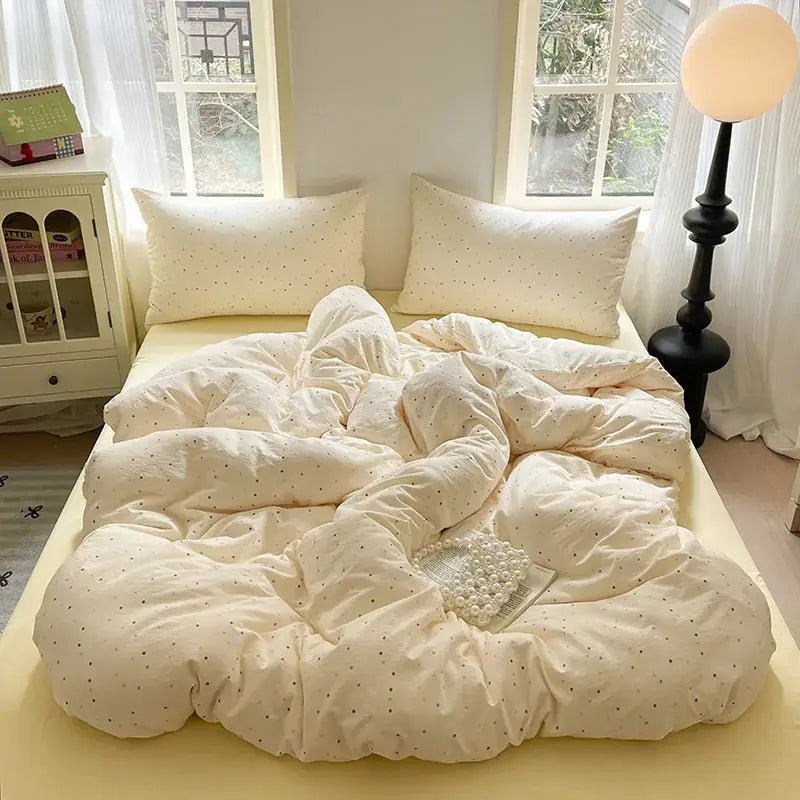 Cream-colored plush quilt with subtle black polka dots in a lavender floral textured cotton bedding set