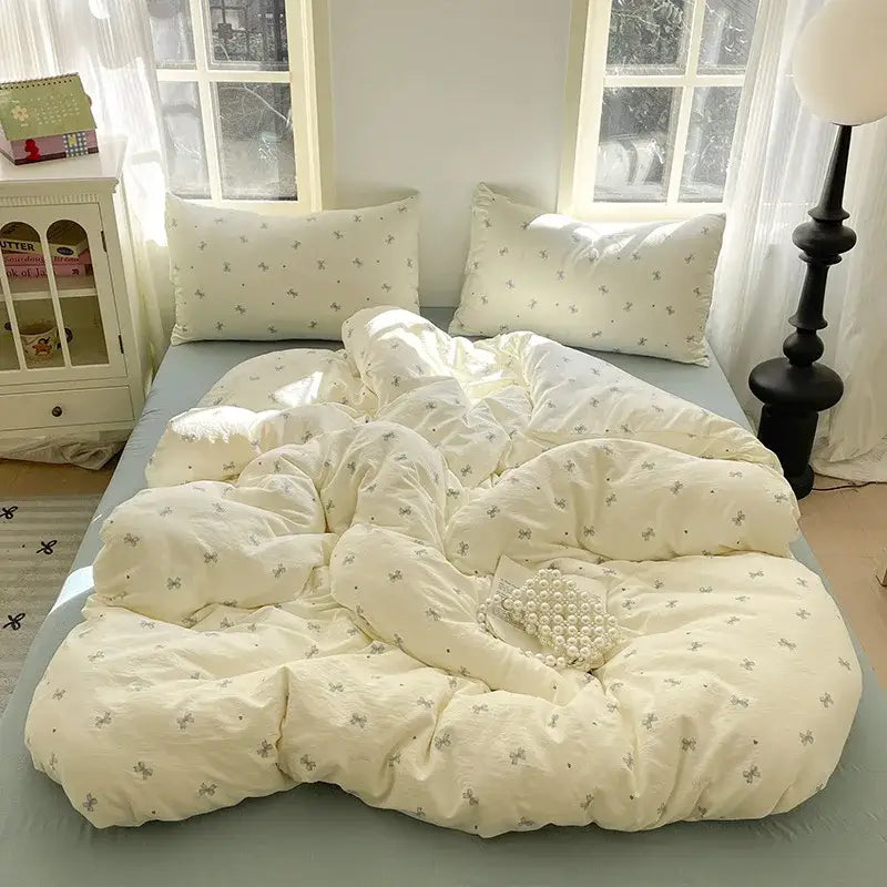 Cream-colored quilt with delicate gray bows from lavender floral textured cotton bedding set for bedroom use