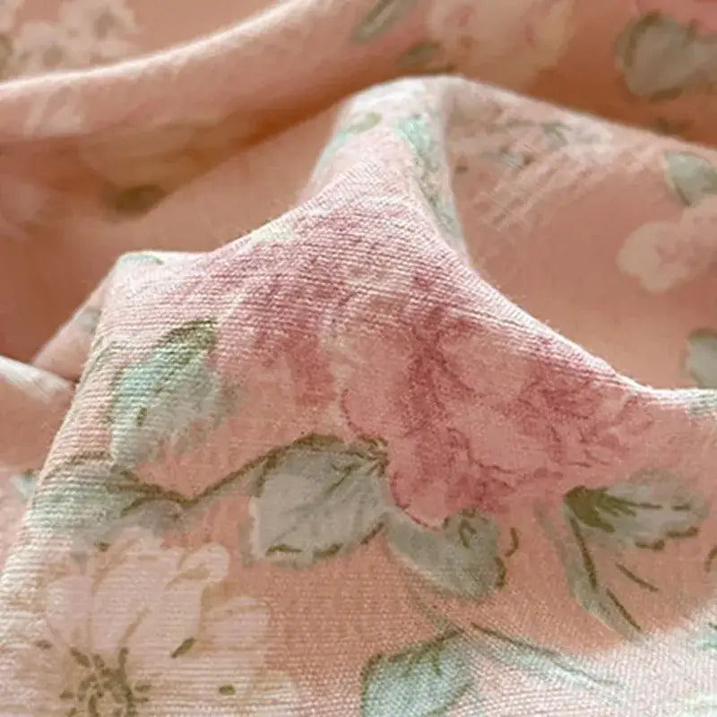 Soft pink cotton bedding set with delicate muted green and beige floral patterns in textured lavender quilt design