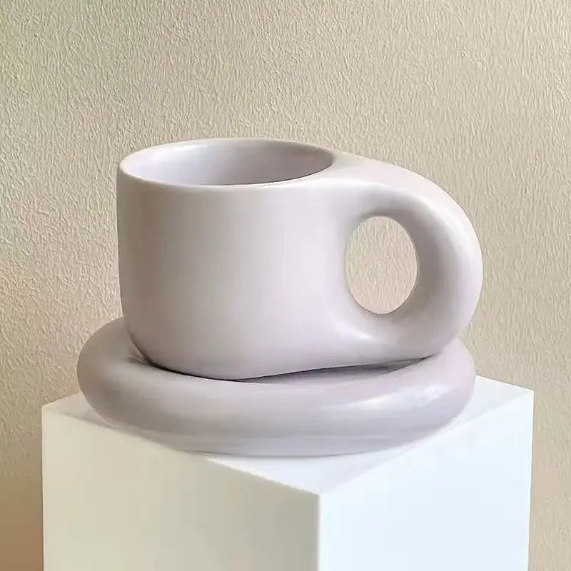 Minimalist white ceramic ink splash mug with smooth rounded handle and matching oval plate from decorbites ink splash set