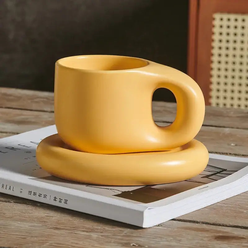 A smooth matte yellow ink splash ceramic mug with rounded handle and matching oval plate from decorbites ink splash set