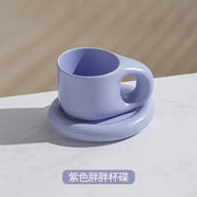 A soft lavender ink splash ceramic mug with a rounded handle on a matching oval plate from decorbites ink splash set