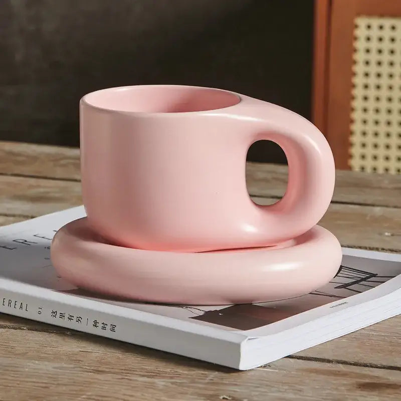 A soft pink ink splash ceramic mug with rounded minimal handle and matching oval plate from decorbites ink splash set