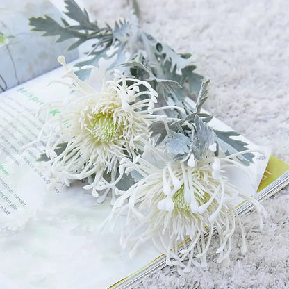 White artificial chrysanthemum flowers with silvery-gray foliage on a lavender and orange artificial crab claw branch decorbites artificial crab for wedding decor