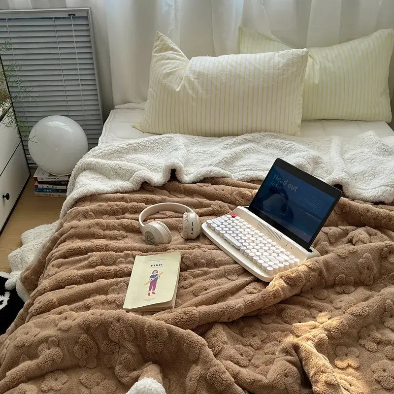 White laptop keyboard with screen displaying head out next to lavender and white cozy lamb wool flower throw blanket decorbites cozy lamb