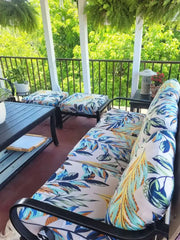 Black metal-framed outdoor sofa with vibrant blue teal and orange leaf pattern brushed knit cushion cover for patio decor