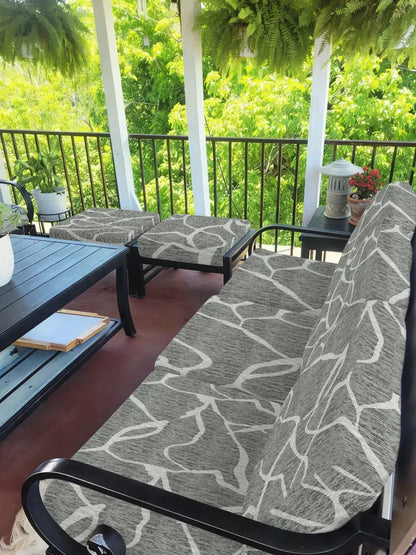 Gray and white leaf pattern brushed knit outdoor sofa cushion cover on a black metal frame patio sofa