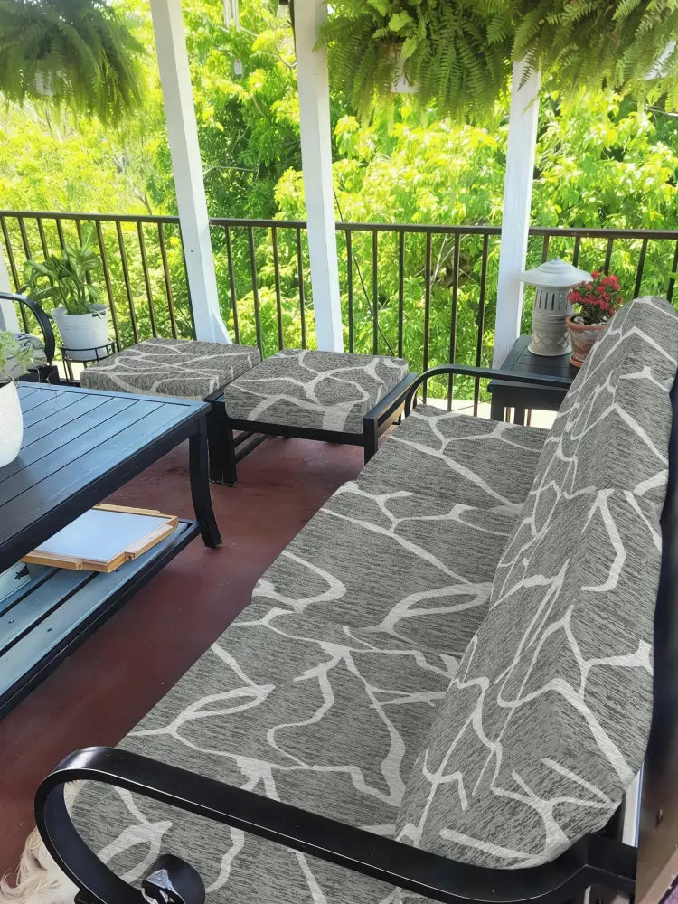 Gray and white leaf pattern brushed knit outdoor sofa cushion cover on a black metal frame patio sofa