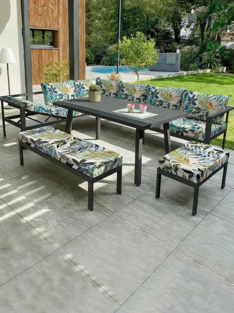 Outdoor patio set with dark gray metal frame and vibrant tropical leaf pattern brushed knit sofa cushion cover